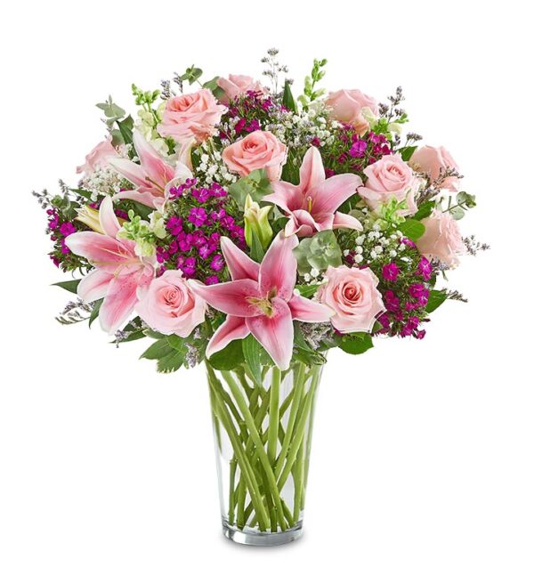 The Amaze Her Bouquet by Fleuriste Terrafolia Flowers features oriental lilies, pink roses, purple blooms, babys breath, and lush foliage in a clear glass vase—fresh and elegant against a white background.
