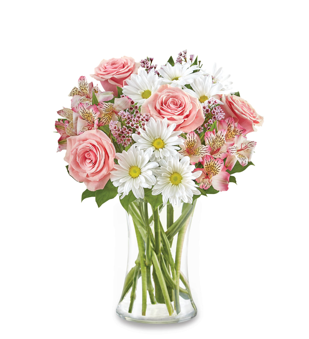 The She’s Special Bouquet by Fleuriste Terrafolia Flowers features pink roses, white daisies, and Peruvian lilies artfully arranged with lush greenery in a clear glass vase, set against a crisp white background.