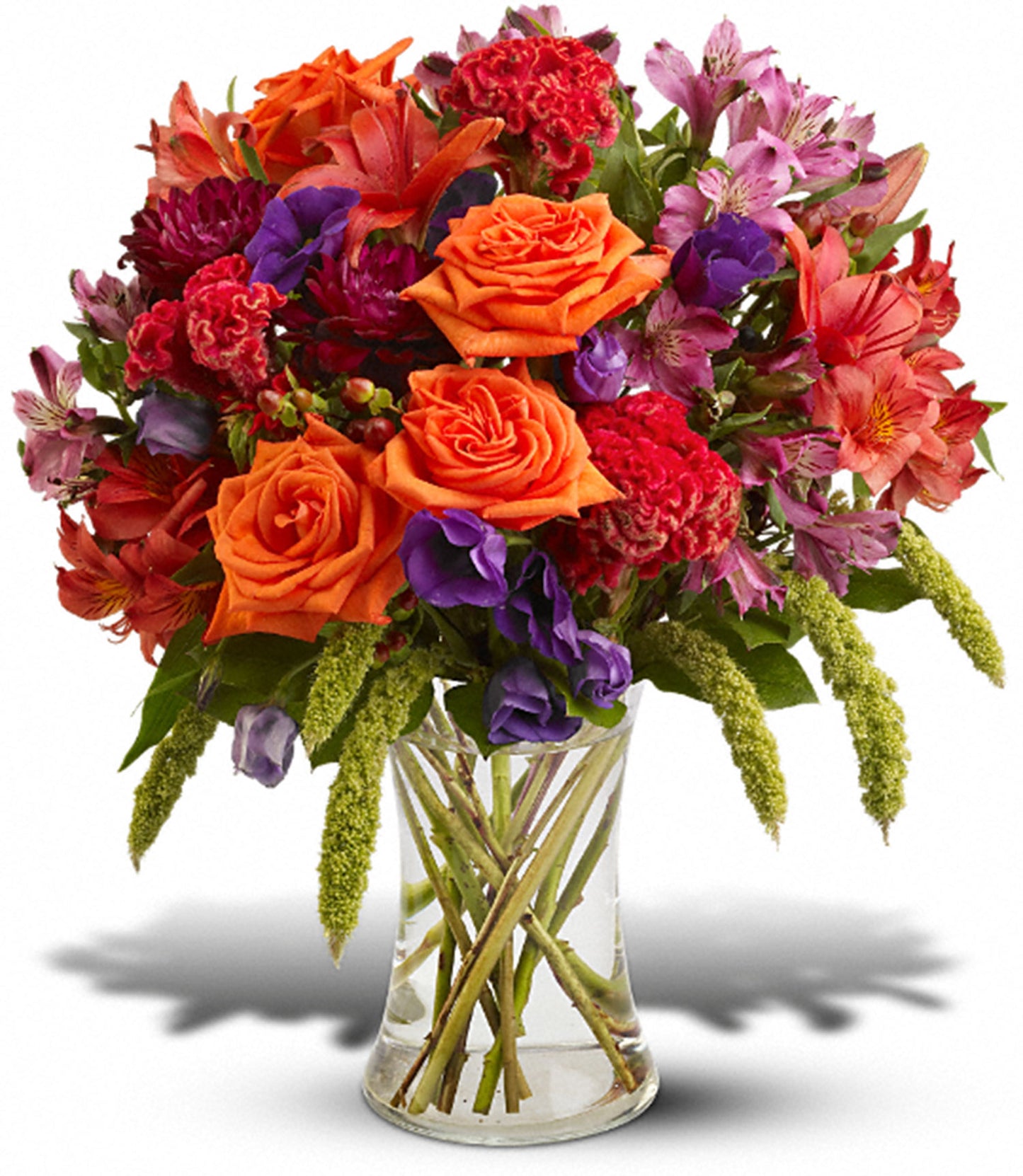 The TF Autumn Gemstones arrangement features a clear glass gathering vase filled with vibrant orange roses, red Asiatic lilies, purple and red flowers, and lush greenery for a colorful display.