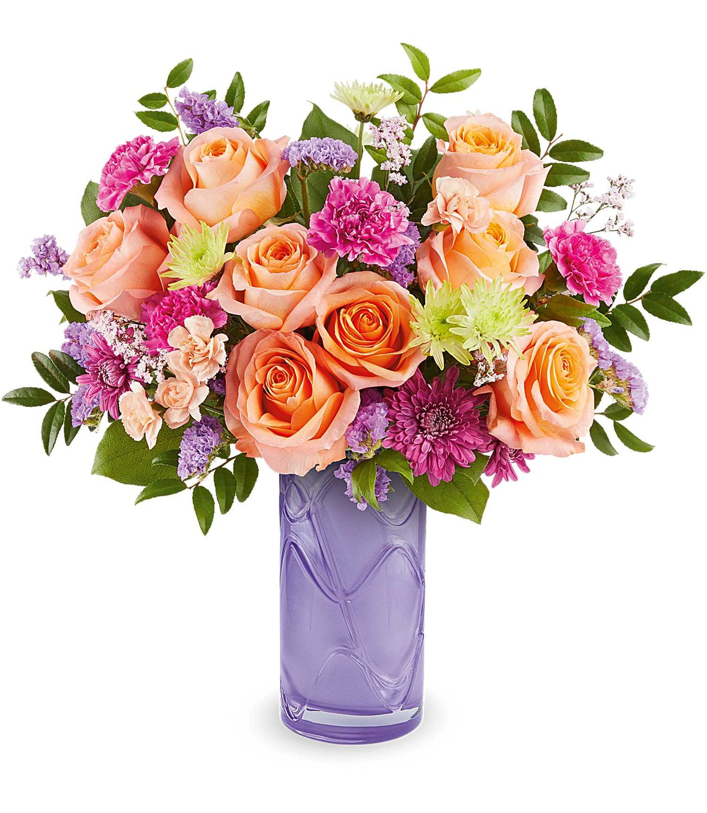 The Pretty Daydream Bouquet features fuchsia carnations, peach roses, and purple blooms with green leaves in a tall, textured vase.