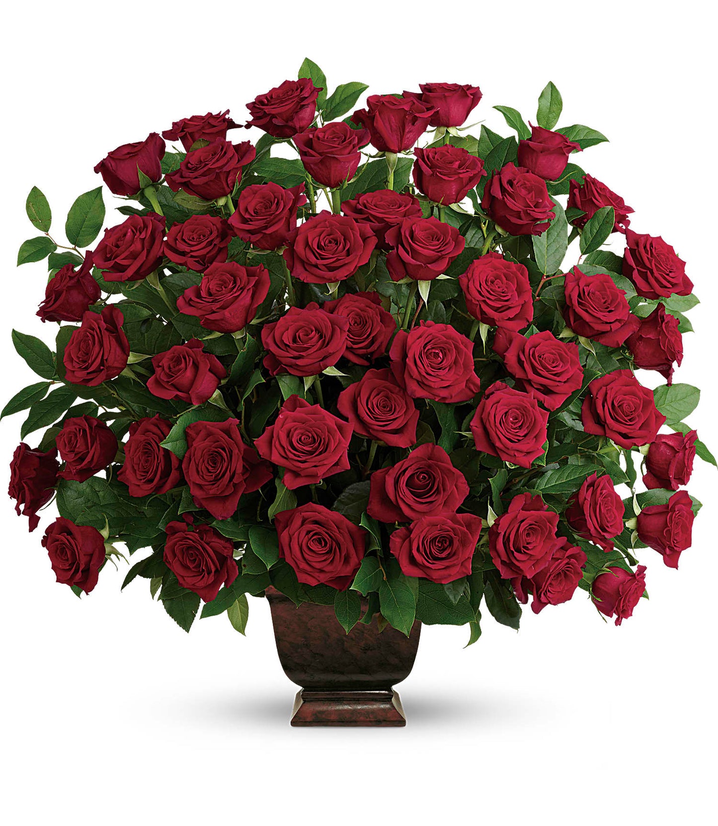 The Rose Tribute Bouquet features vibrant red roses and lush salal leaves elegantly arranged in a dark brown Noble Heritage Urn, presented against a plain white background.