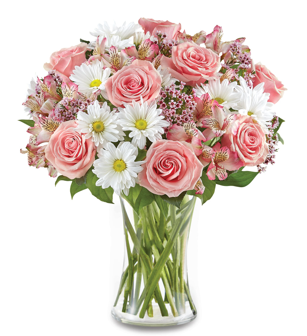 The She’s Special Bouquet by Fleuriste Terrafolia Flowers features pink roses, white daisies, and Peruvian lilies artfully arranged with lush greenery in a clear glass vase, set against a crisp white background.