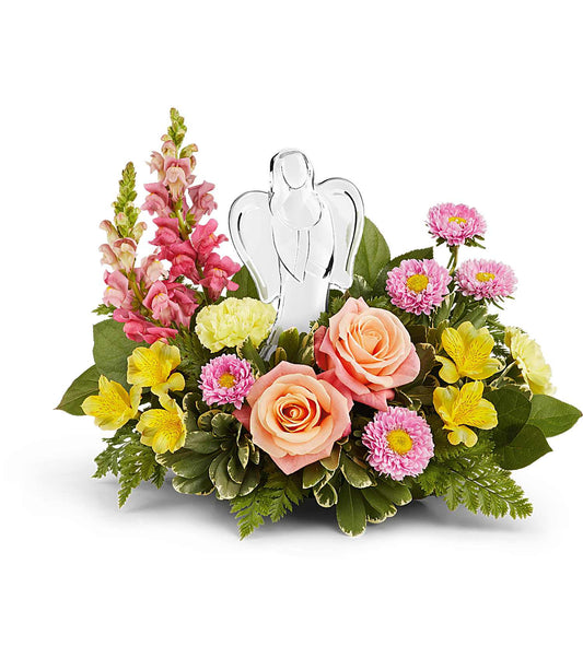 The Angel's Embrace Bouquet showcases pink roses, yellow alstroemerias, pink asters, snapdragons, and greenery. A clear glass angel keepsake stands at the center of this stunning arrangement.