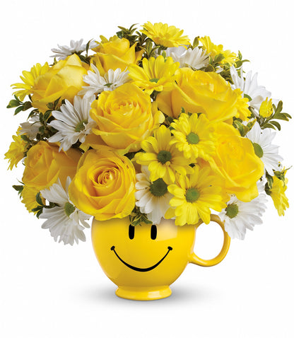 The Be Happy Bouquet by TF features a bright yellow Be Happy® Mug filled with cheerful yellow roses, yellow daisies, and white daisies for a vibrant arrangement.