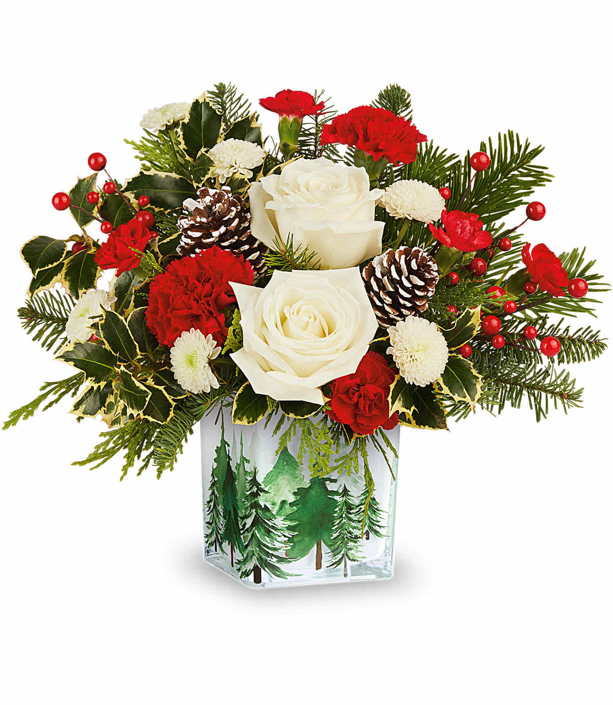 Evergreen Glow Bouquet featuring white roses, red carnations, pine cones, and holly arranged in a glass cube vase decorated with a forest scene.