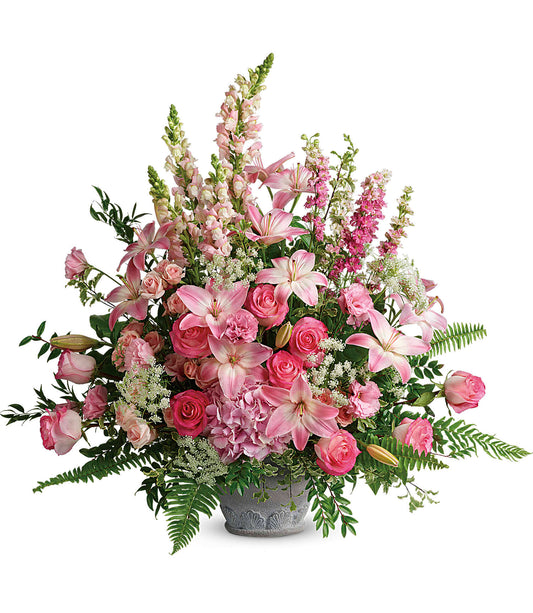 The Graceful Glory Bouquet is a large pink flower arrangement in a gray Parisian Garden Pot, featuring lilies, roses, and snapdragons with lush greenery and ferns in various shades of pink and white.