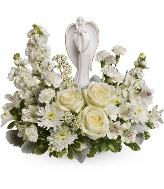 The TF Guiding Light Bouquet features a white porcelain Angel of Grace surrounded by white roses, chrysanthemums, carnations, and greenery for a serene and elegant sympathy display.