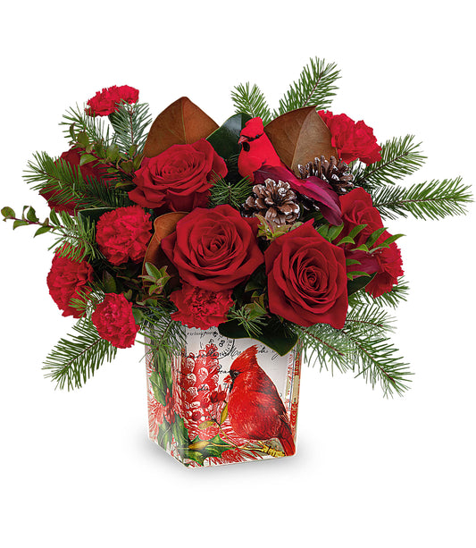 The Joyful Cardinal Bouquet by Fleuriste Terrafolia Flowers features festive red roses, carnations, pine branches, pinecones, and a cardinal decoration in a square vase with a charming cardinal illustration.