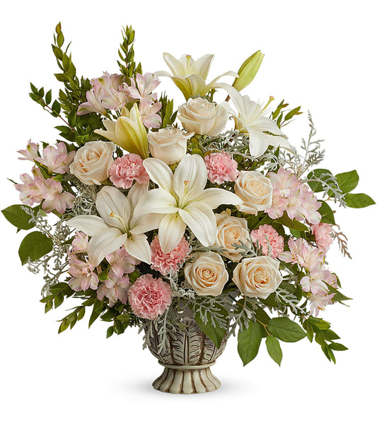 The Peaceful Joy Bouquet features white asiatic lilies, pale pink roses, pink carnations, crème roses, and assorted greenery for a soft, elegant display.