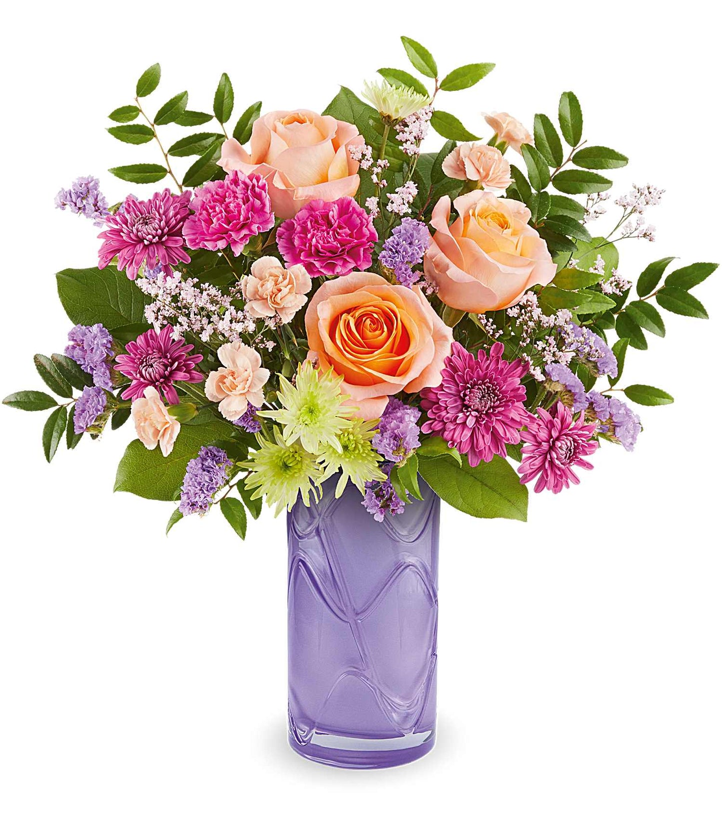 The Pretty Daydream Bouquet features fuchsia carnations, peach roses, and purple blooms with green leaves in a tall, textured vase.