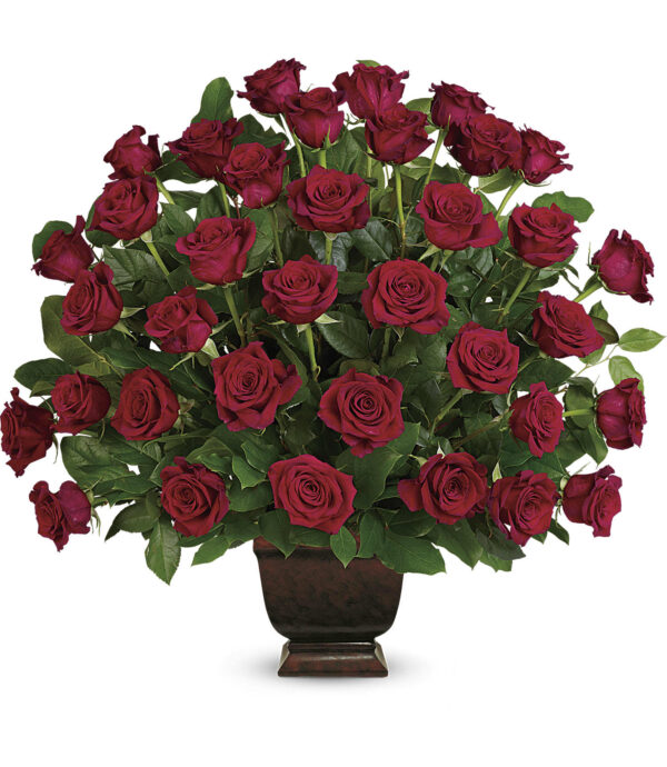 The Rose Tribute Bouquet by Fleuriste Terrafolia Flowers features deep red roses and lush salal leaves, artfully arranged in a dark brown Noble Heritage Urn against a white background.
