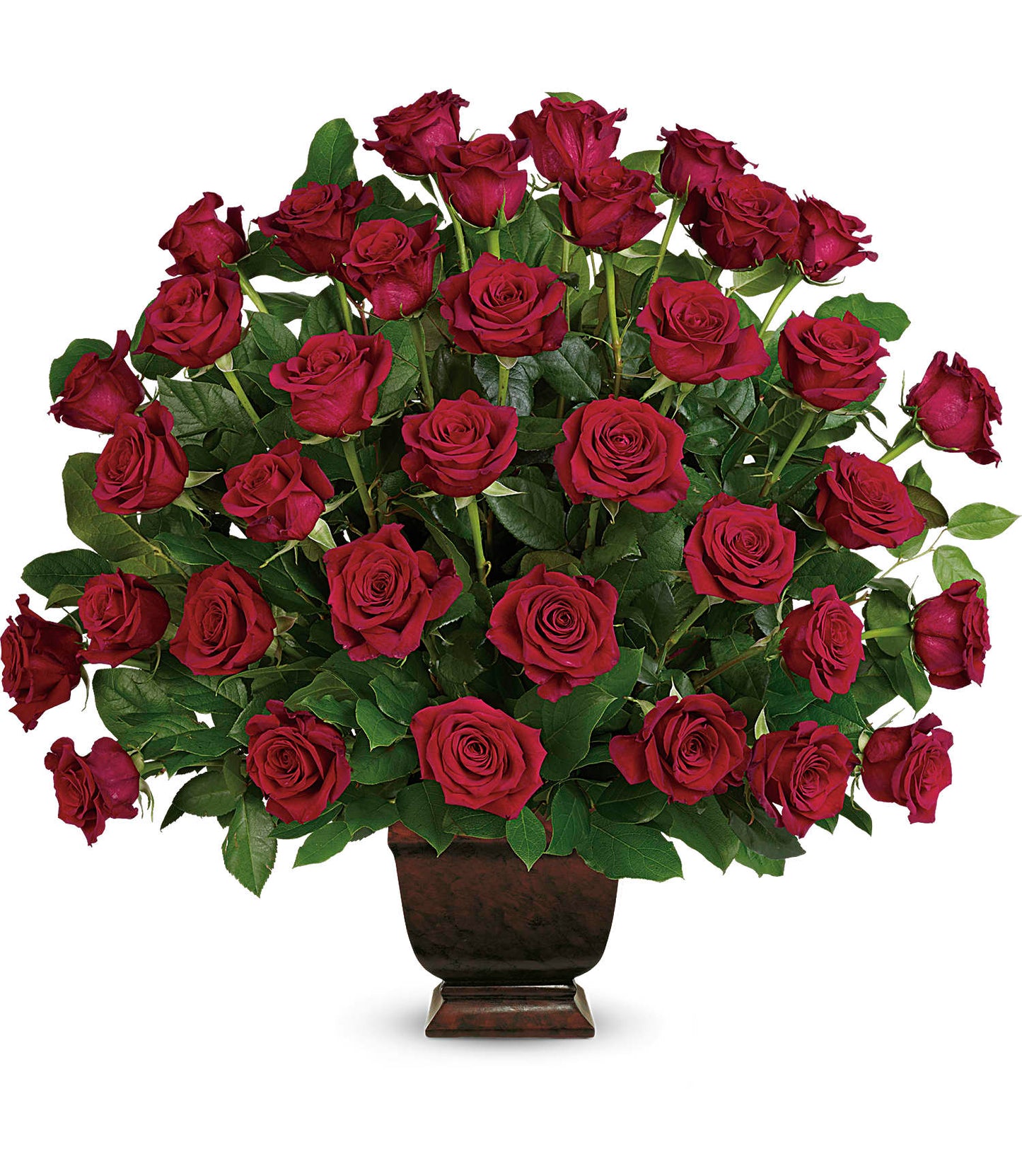 The Rose Tribute Bouquet features vibrant red roses and lush salal leaves elegantly arranged in a dark brown Noble Heritage Urn, presented against a plain white background.