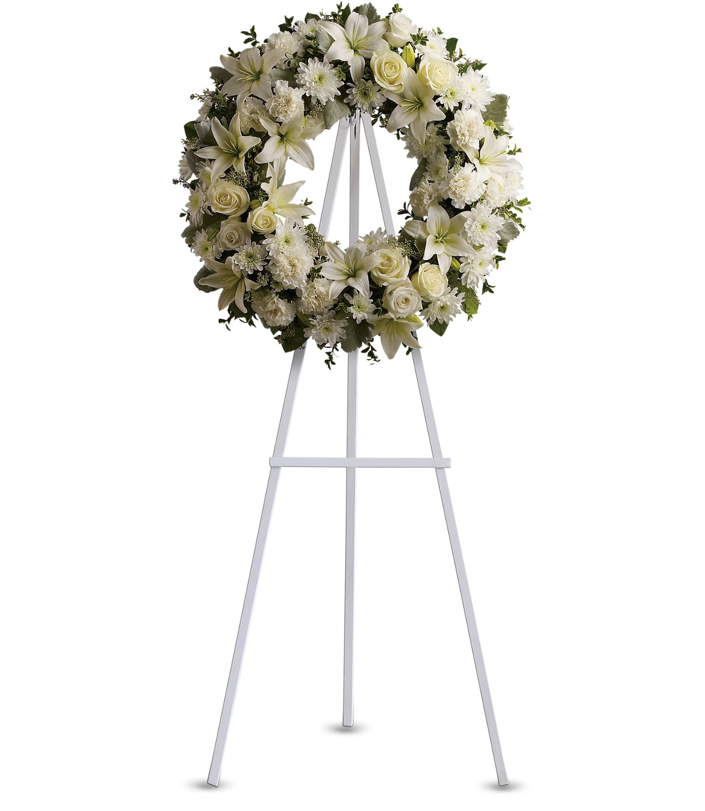 The TF Serenity Wreath, featuring fresh white roses and lilies, is displayed on a tall white metal easel against a plain white background.