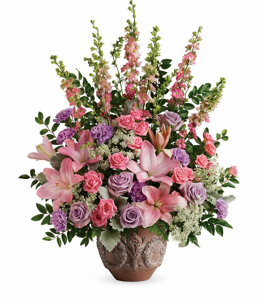 The Soft Blush Bouquet features a decorative ceramic vase filled with pink asiatic lilies, pink and lavender roses, purple carnations, and greenery for an elegant, colorful touch.